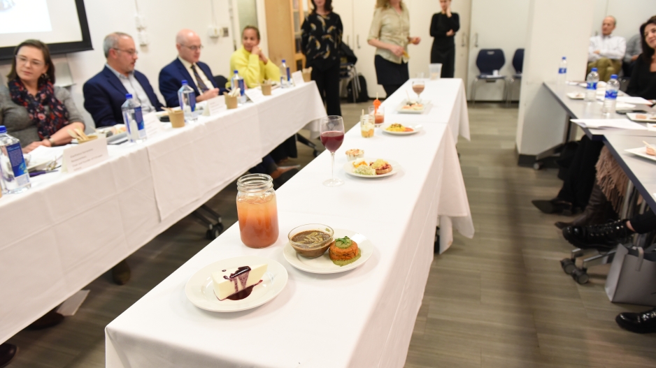 Each team's meal laid out on a long table covered with a white table cloth located in front of the judges.
