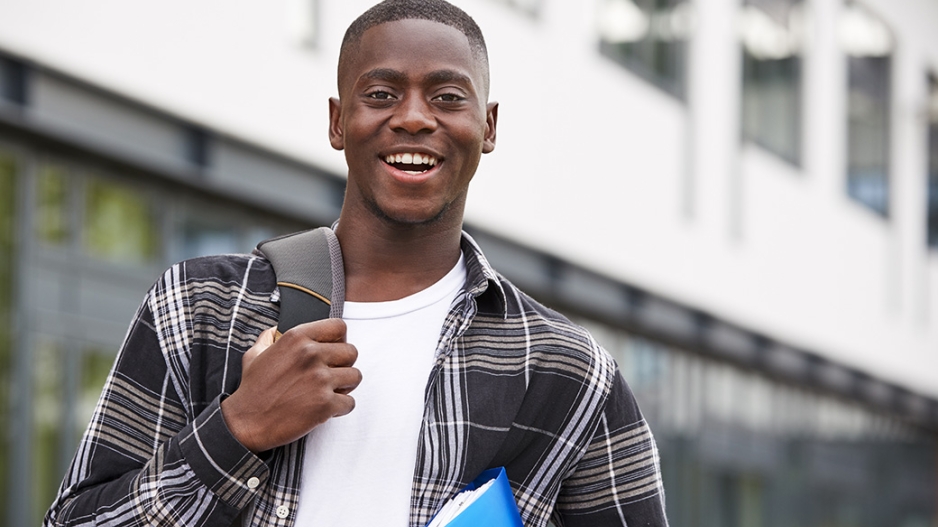 Black student with backpack and notebook smiling