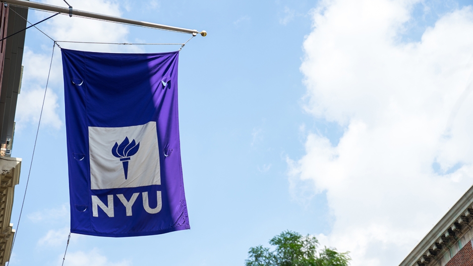 NYU flag flying against a blue sky