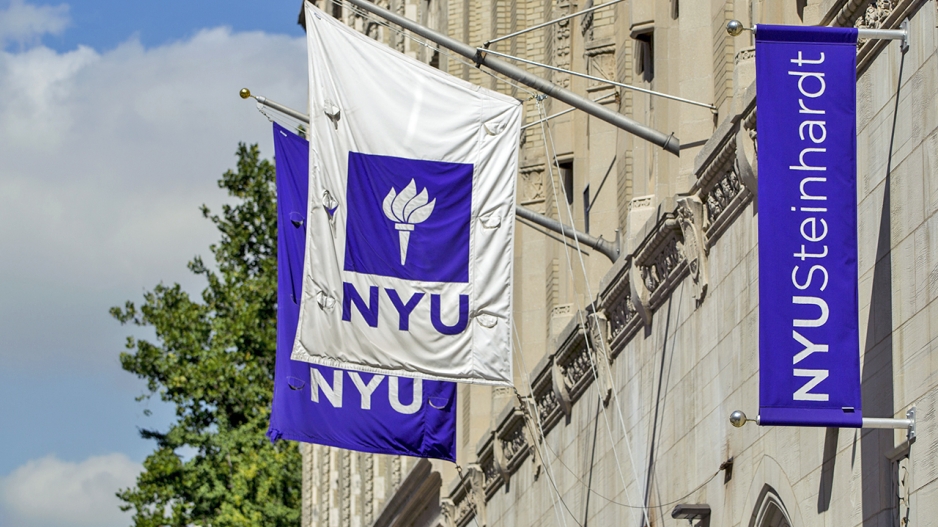 NYU flags flying on the side of a building