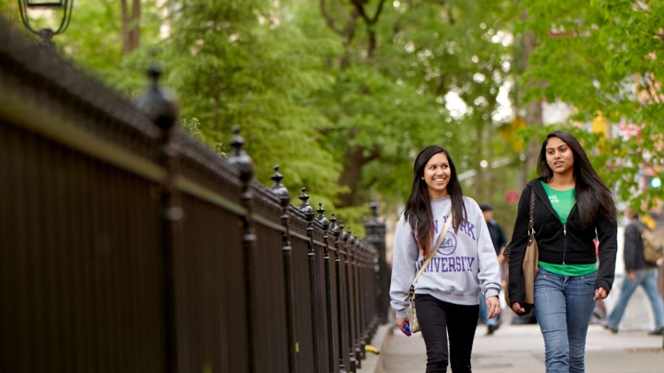 Two undergraduates walking along the outside of Washington Square Park