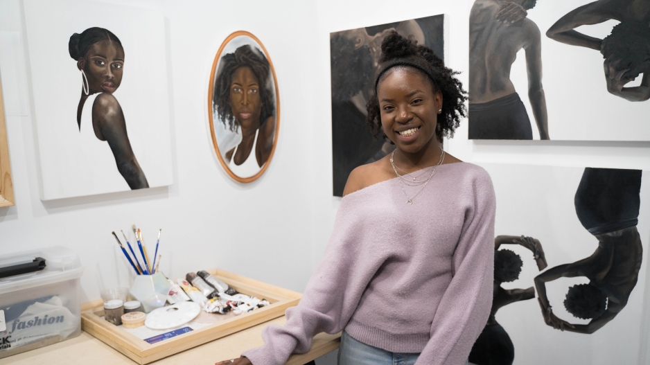 BFA student in studio with paintings.