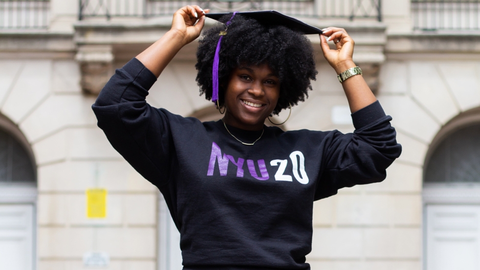 Kyra wearing an NYU20 shirt and a graduation cap with a violet tassel.