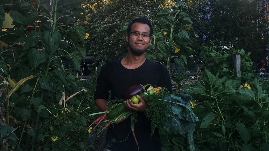 Tot holding an armful of produce grown on the NYU Urban Farm Lab during his time in the Food Studies program.