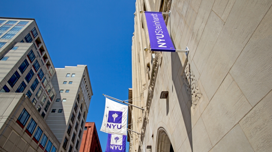 a view from below showing NYU banners against a blue sky