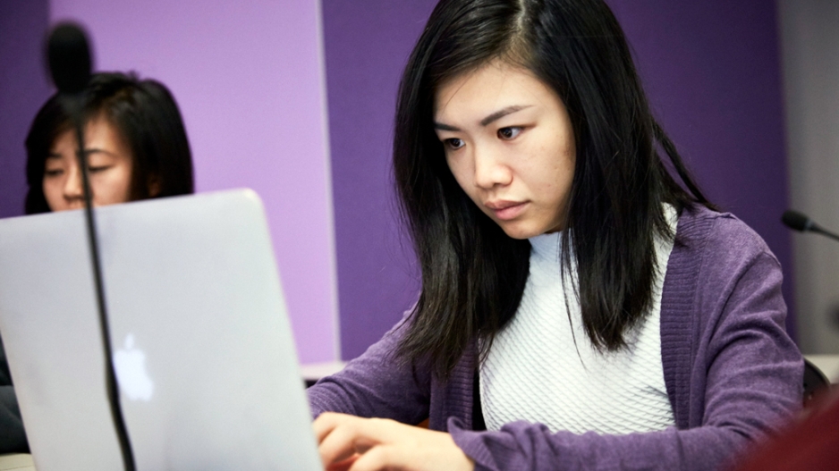 An Asian American woman working at a laptop