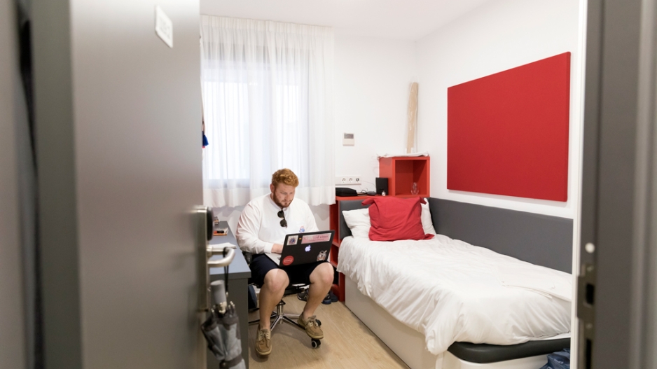 A student working on a laptop in his dorm room