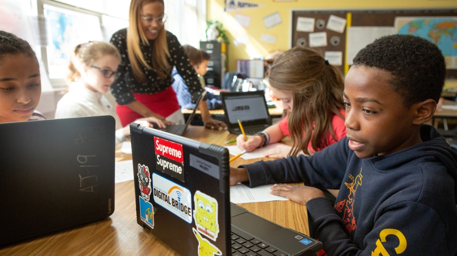 Students at a middle school use online research to answer questions during a lesson in history class.