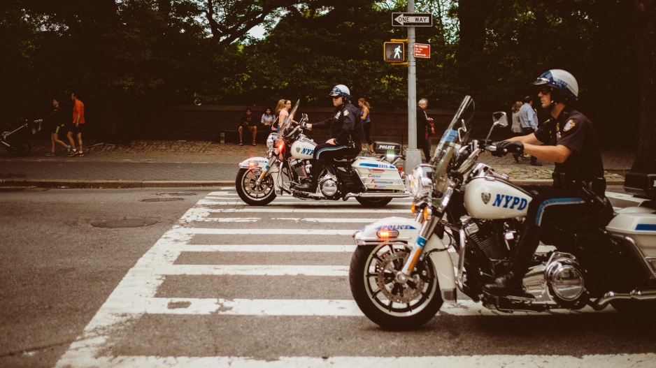 Two NYPD officers on motorcycles at a crosswalk outside of Central Park