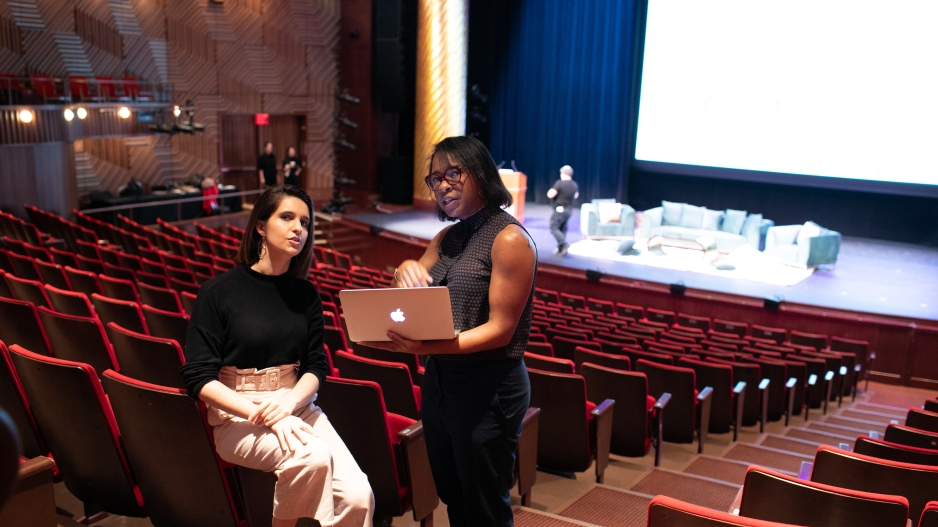 Two students in a theatre looking at a laptop