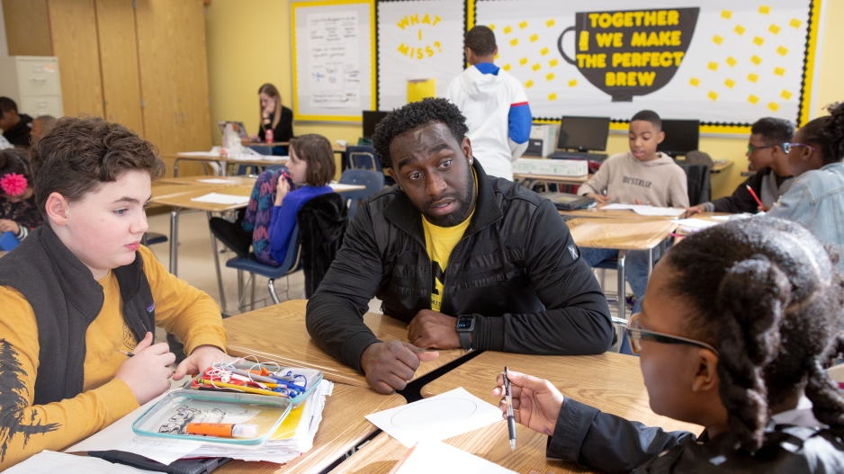 A black teacher works with a white student and a black student in a small group