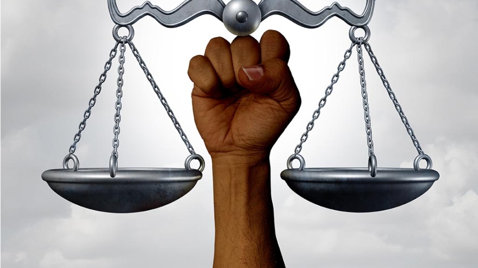 Black person’s hand holding up the scales of justice