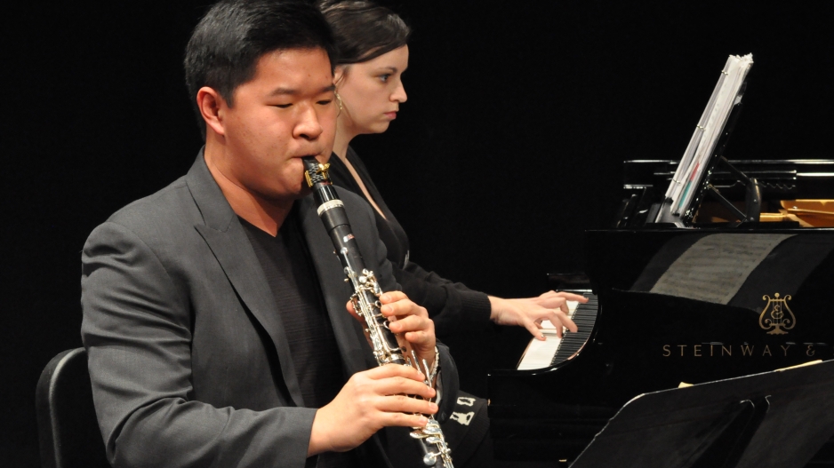 Clarinetist performing with pianist in the background