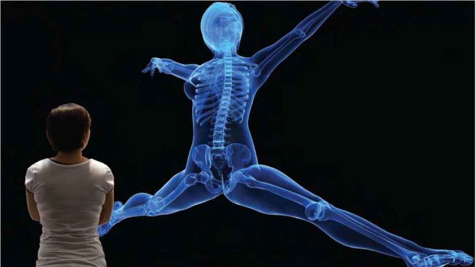A woman with her back turned facing a projection of an x-ray of a human with its legs and arms spread wide