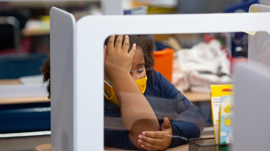 A second-grade student rests her head on her hand during a lesson.
