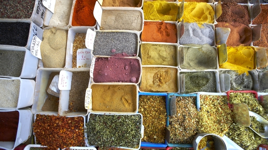 A photo from above of many containers of multicolored spices