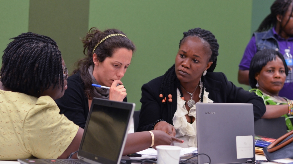 A photo from the global internship program in Ghana. Four women sit together at a table over laptops and notes.