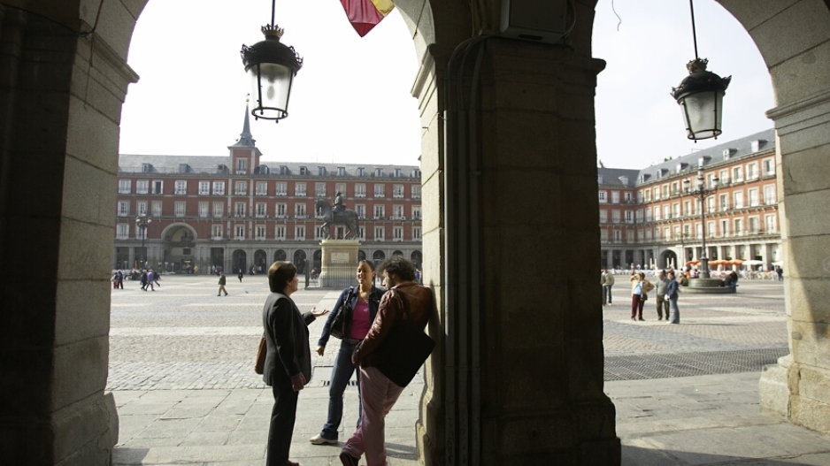 Three students stand and talk in the Plaza Mayor in Madrid, Spain.