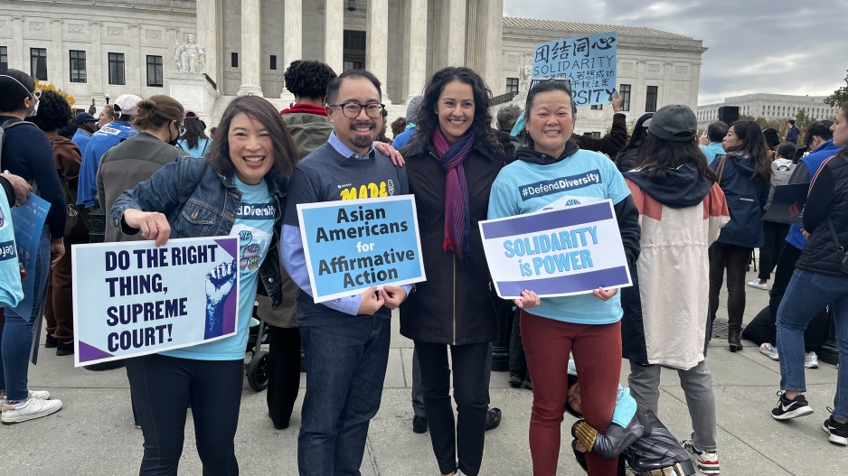 A photo of four professors, including Mike How Nguyen, holding signs in support of affirmative action on the steps of the Supreme Court.