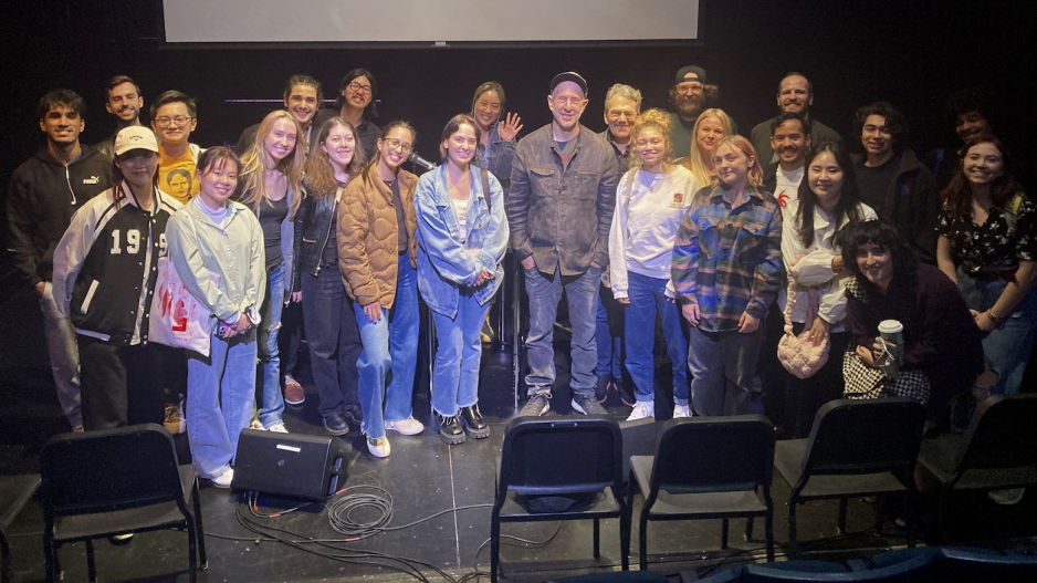 Musician Sam Hollander surrounded by NYU Songwriting students