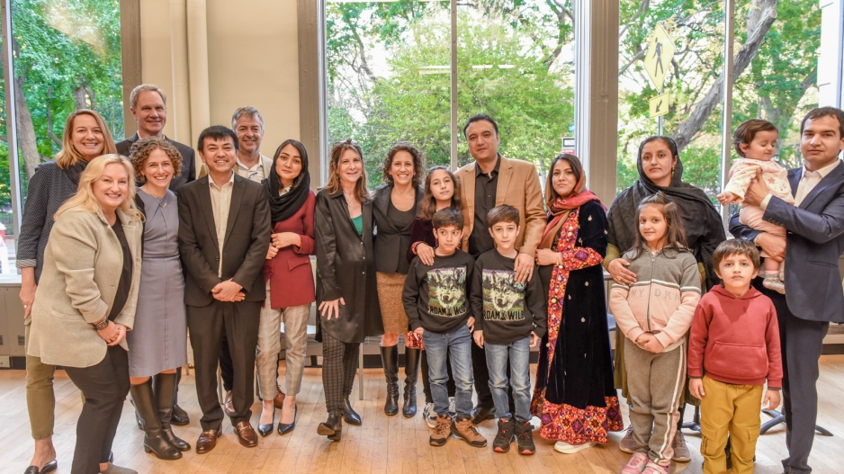 A group of people, including three scholars from Afghanistan and their families and faculty and administrators from NYU Steinhardt, stand in a group and smile for the camera.