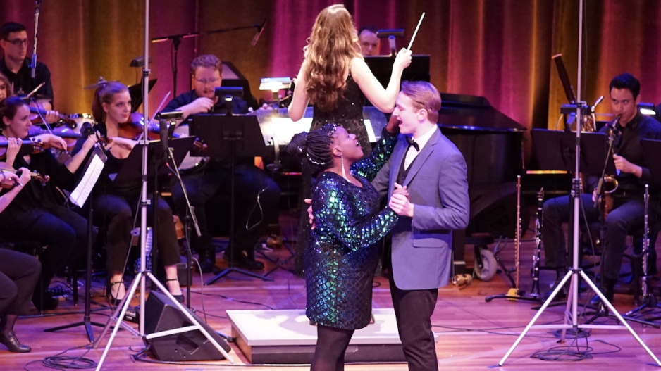 Couple embracing while singing in front of orchestra