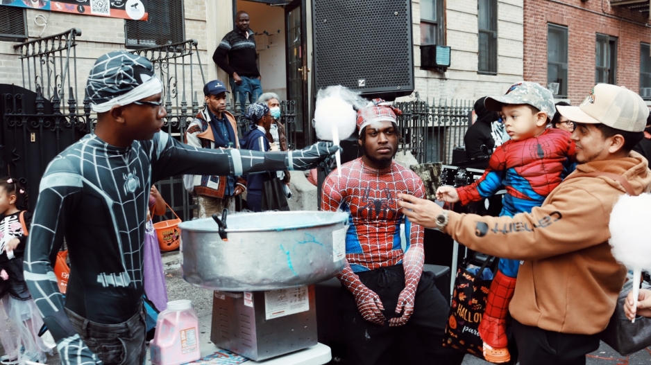 Group of people dressed as Spiderman giving a young boy dressed as Spiderman cotton candy.