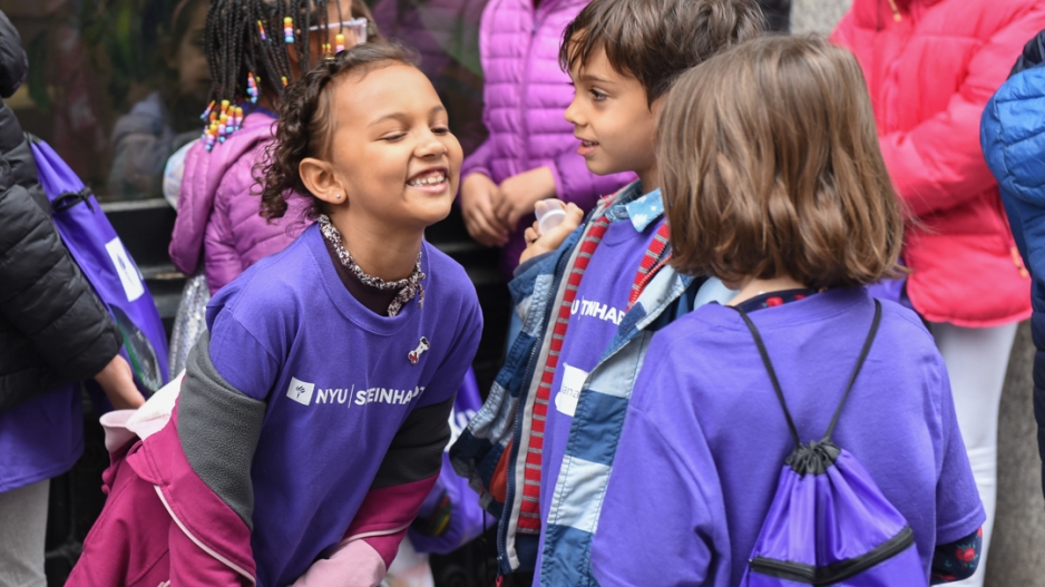 A trio of children in purple NYU Steinhardt shirts. 
