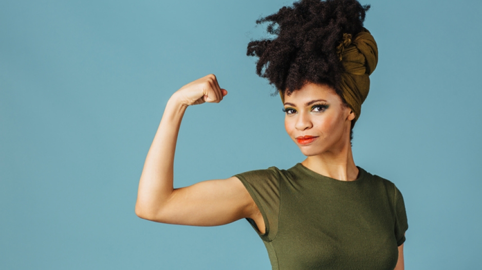 A Black woman flexing her bicep, showing strength.