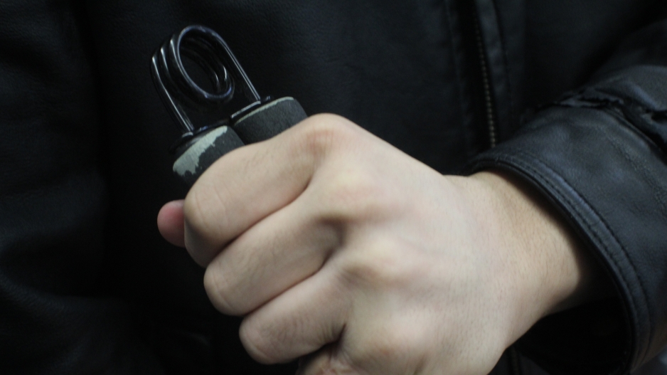 Photograph of a fist holding a grip strengthener. 