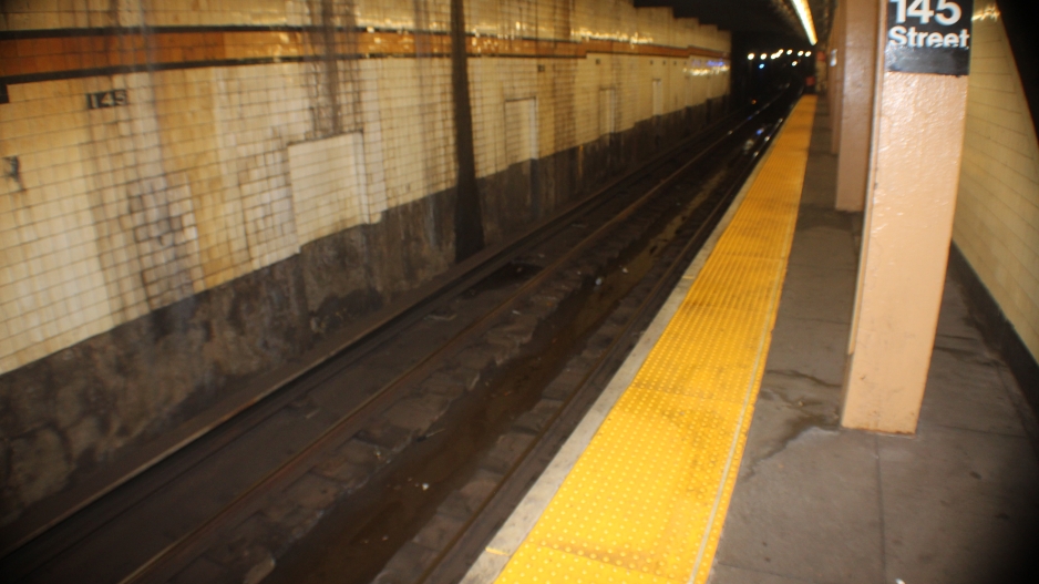 Fish eyes photograph of an empty subway station at 145 street, with the railroad tracks beginning on the lower left and going off into the distance on the upper right of the picture. 