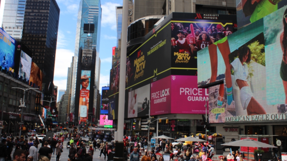  Photograph of Times Square going down Broadway during the daytime with many people. 