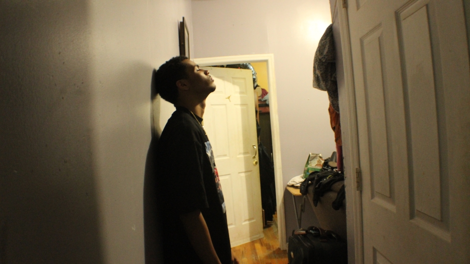 Photo captures frustrated male teenager. He is standing against the wall, with his back in exasperation. 
