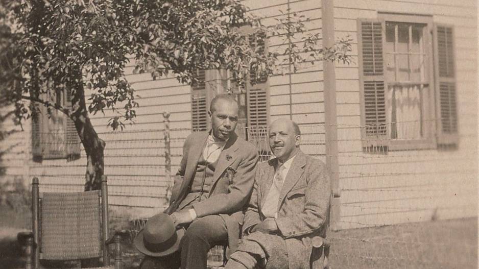 A photo of James Weldon Johnson and W.E.B. Du Bois sitting outdoors behind a home