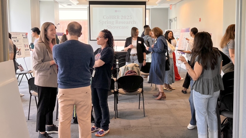 People standing and chatting in small groups in a conference room at CoHRR's 2025 spring showcase