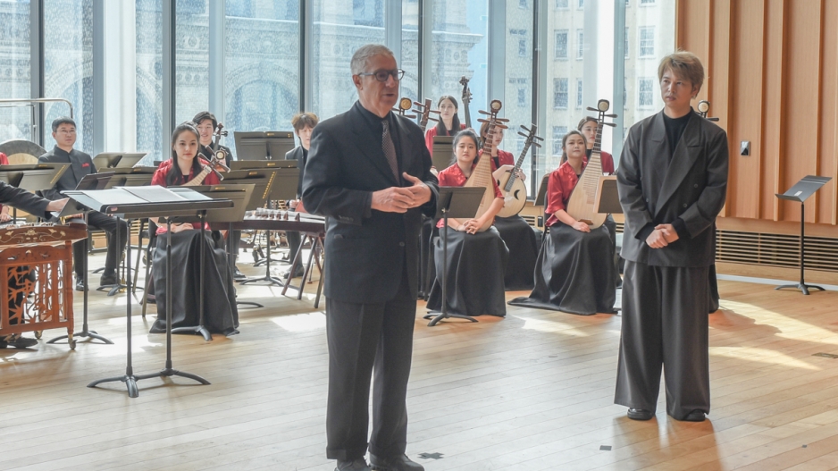 Percussion director standing in front of visiting Chinese musical artists leading a discussion