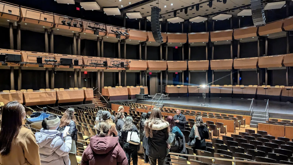 Students standing in back of large lincoln Center jazz auditorium looking at the venue with all its balconies.