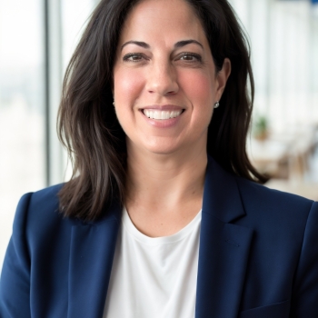 Caucasian woman with dark medium length hair in white blouse and blue blazer