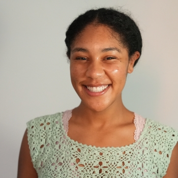 Picture of woman smiling standing against white background in crocheted top