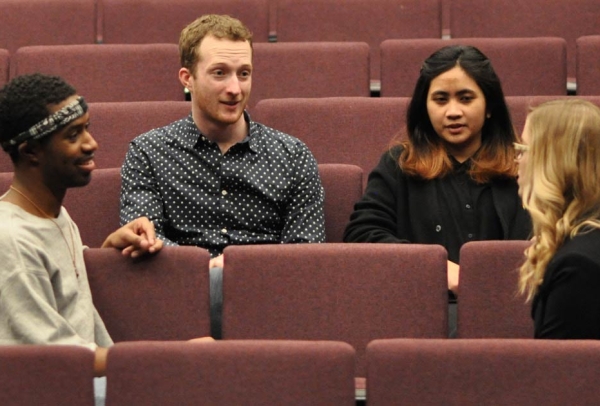 Students sitting in a theatre talking to one another