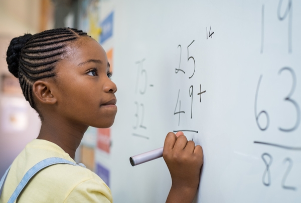 Black student solves math problems on a white board