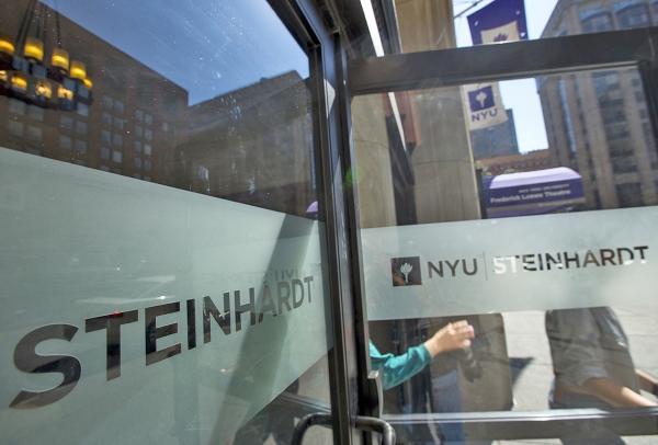 Students walking out of an open door labelled with NYU Steinhardt