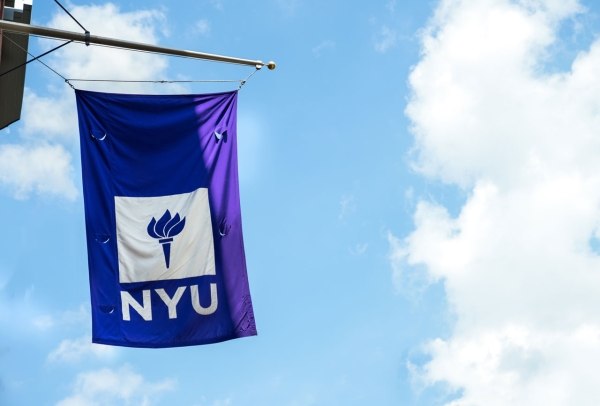 The NYU flag flying against a bright blue sky