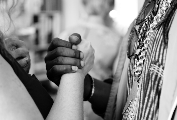 closeup of a black person and a white-passing person clasping hands