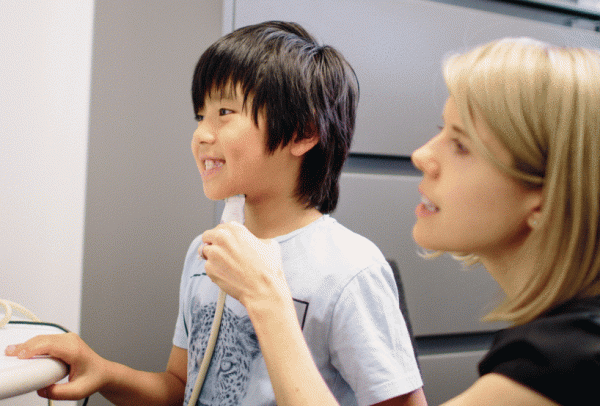 Dr. Tara McAllister holding a biofeedback device under the chin of a young boy.