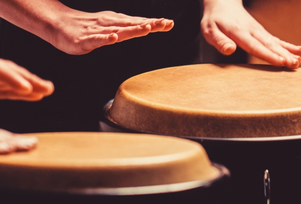 Closeup of two people's hands playing 2 conga drums
