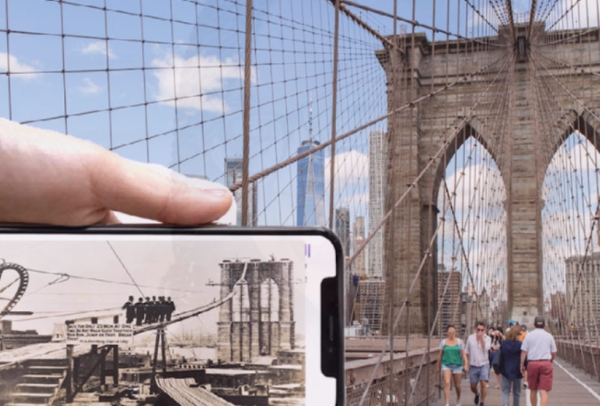 Brooklyn Bridge behind a Mobile phone with historical photo of the bridge