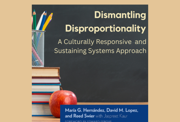 Image serves a book cover for "Dismantling Disproportionality: A Culturally Responsive and Sustaining Systems Approach " Cover image feature book title written on a chalkboard. The chalkboard is behind a teachers desk, with features books, pencil, and an apple on it.