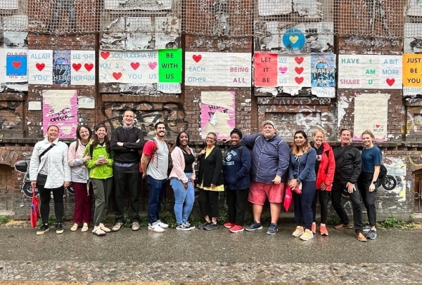 A group of Astor Fellows stand in front of a wall with encouraging and uplifting signs on it