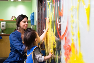 Art teacher helping a young child do finger painting